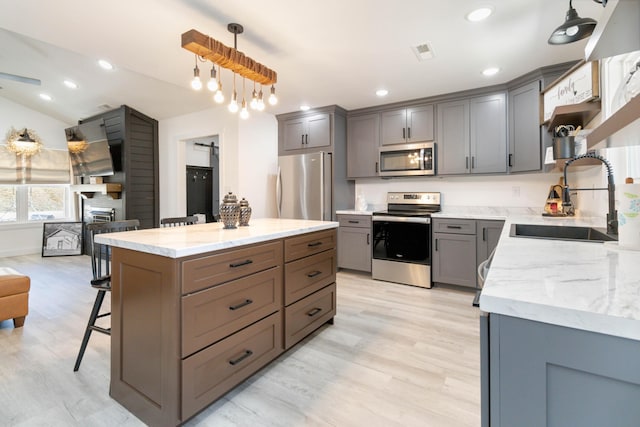 kitchen featuring pendant lighting, sink, gray cabinets, appliances with stainless steel finishes, and light hardwood / wood-style floors