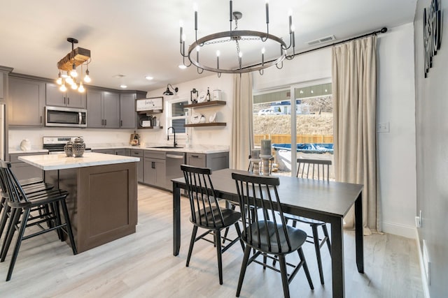 dining space with sink, a chandelier, and light hardwood / wood-style floors