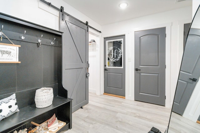 mudroom with a barn door and light wood-type flooring