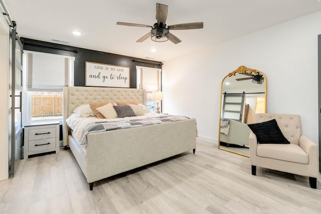 bedroom featuring wood-type flooring, a barn door, and ceiling fan