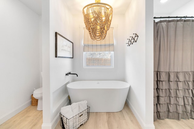 bathroom with hardwood / wood-style floors, toilet, a chandelier, and separate shower and tub