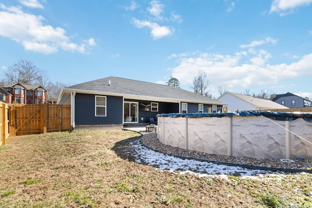 rear view of property with a covered pool and a lawn