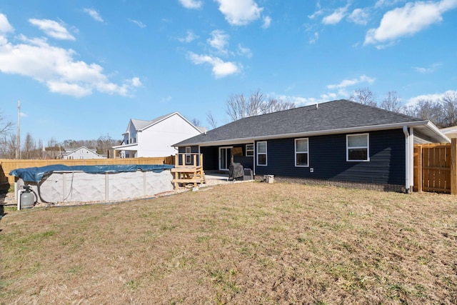 rear view of house with a covered pool and a yard