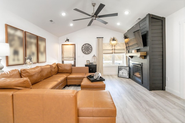 living room featuring hardwood / wood-style floors, vaulted ceiling, a large fireplace, and ceiling fan