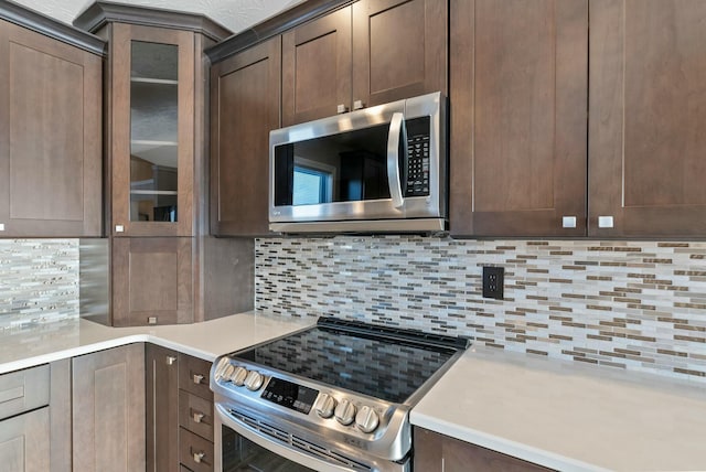 kitchen featuring dark brown cabinetry, stainless steel appliances, and decorative backsplash