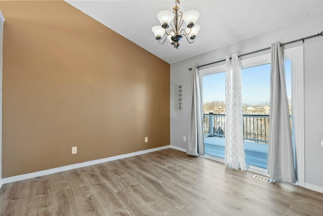 unfurnished room with lofted ceiling, light hardwood / wood-style floors, and a chandelier