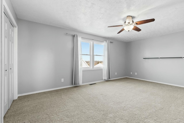 carpeted empty room with a textured ceiling and ceiling fan