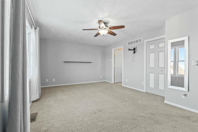 spare room with ceiling fan, light colored carpet, and a textured ceiling