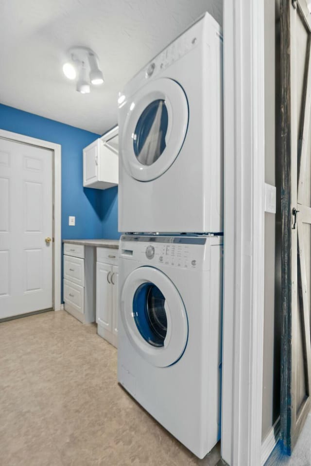 laundry area featuring stacked washer and dryer and cabinets