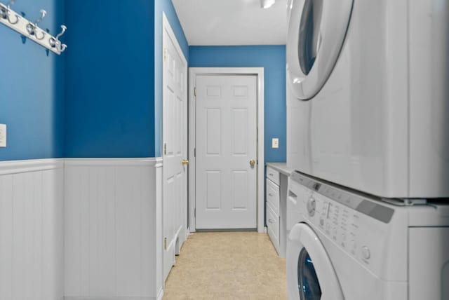 clothes washing area with stacked washing maching and dryer