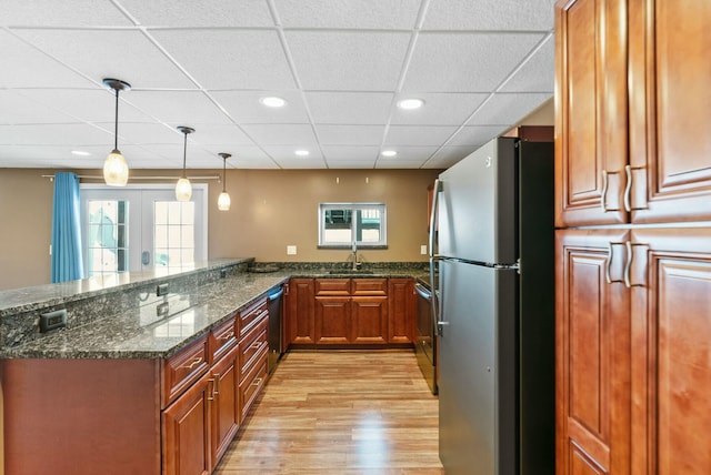 kitchen featuring sink, hanging light fixtures, dark stone counters, kitchen peninsula, and stainless steel appliances