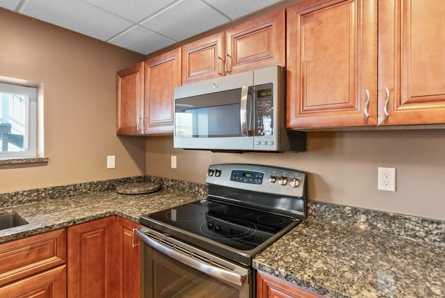 kitchen featuring appliances with stainless steel finishes, sink, a drop ceiling, and dark stone counters