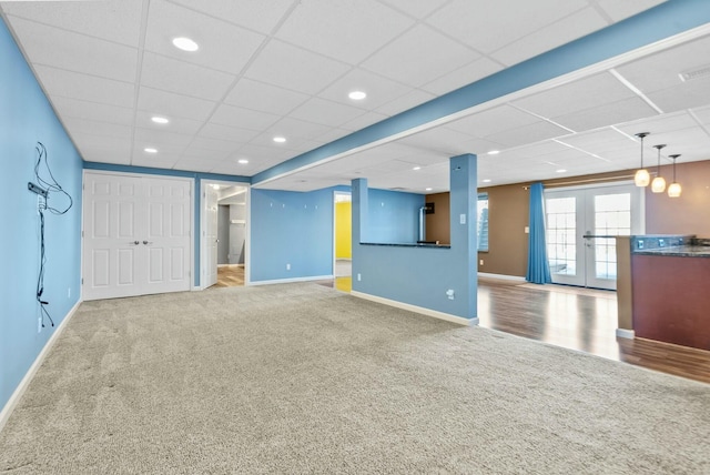 unfurnished living room featuring carpet floors, french doors, and a paneled ceiling