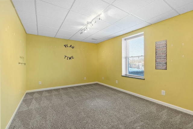 carpeted empty room with track lighting and a drop ceiling