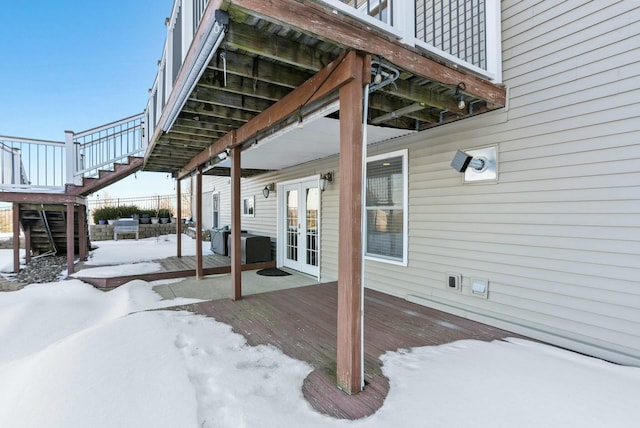 snow covered deck featuring french doors