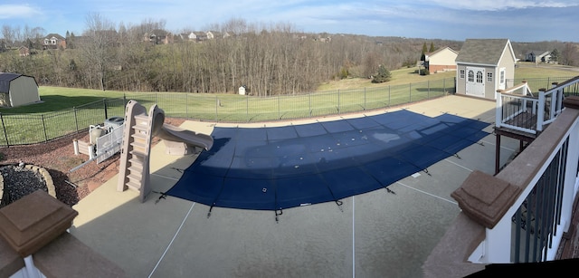 view of pool featuring a water slide, a yard, a patio area, and a shed