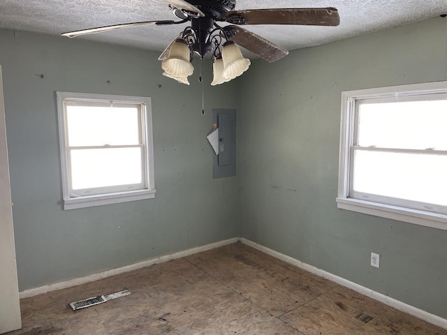 spare room with ceiling fan, a healthy amount of sunlight, electric panel, and a textured ceiling