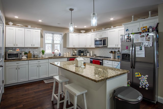 kitchen with white cabinetry, appliances with stainless steel finishes, sink, and hanging light fixtures