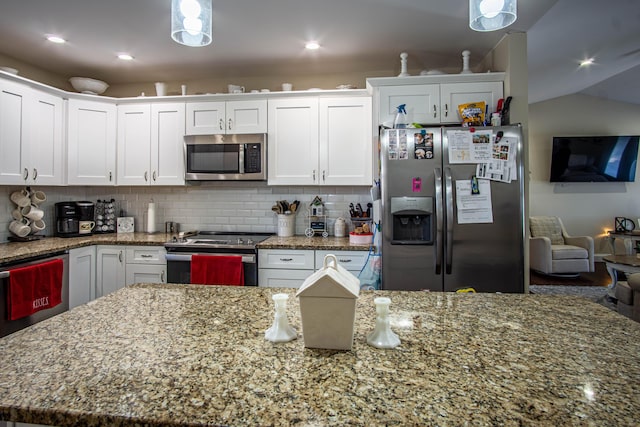 kitchen featuring appliances with stainless steel finishes, white cabinetry, backsplash, light stone counters, and a kitchen island