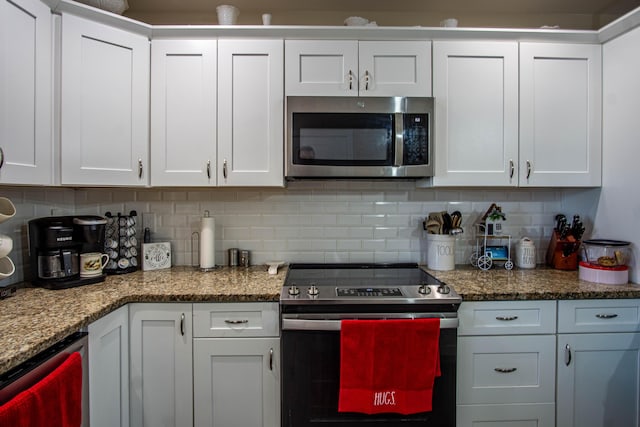 kitchen featuring dark stone countertops, appliances with stainless steel finishes, decorative backsplash, and white cabinets