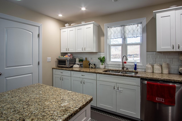 kitchen with white cabinetry, dishwasher, sink, and tasteful backsplash