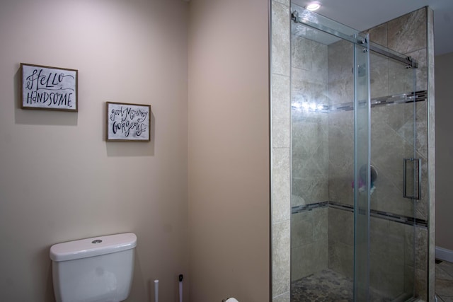 bathroom featuring a shower with door and toilet