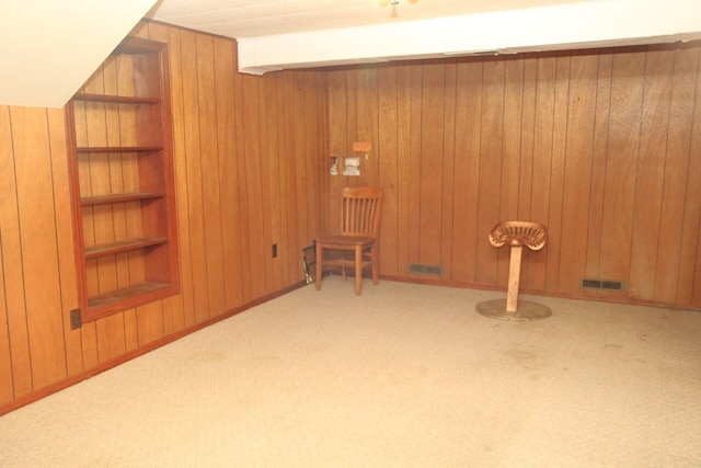 additional living space featuring light colored carpet, built in features, and wood walls