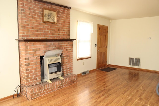 unfurnished living room featuring wood-type flooring and heating unit