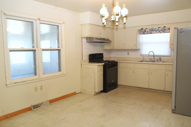 kitchen with stainless steel refrigerator, decorative light fixtures, sink, a chandelier, and black gas stove