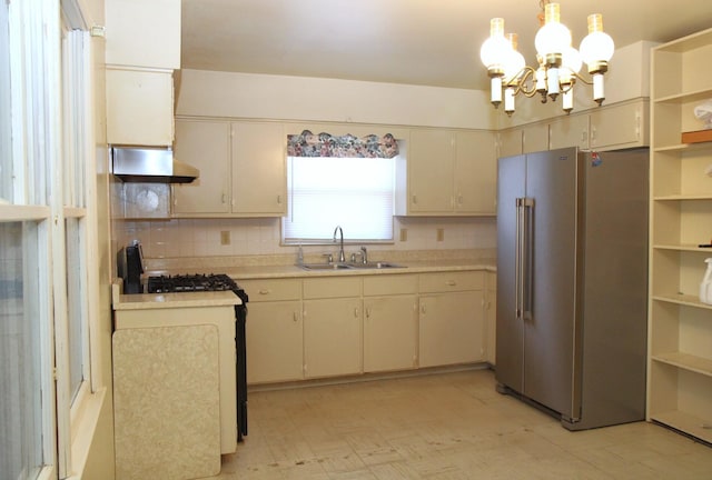 kitchen with sink, tasteful backsplash, decorative light fixtures, a chandelier, and high quality fridge