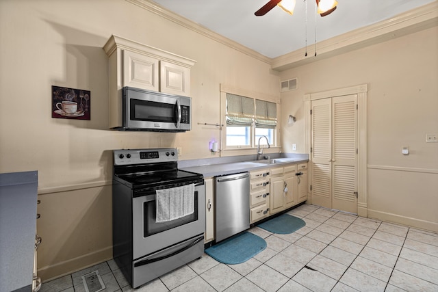 kitchen with sink, crown molding, light tile patterned floors, appliances with stainless steel finishes, and cream cabinetry