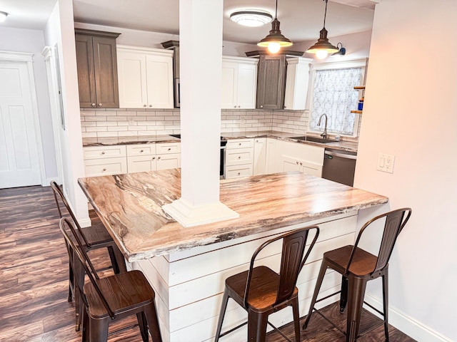 kitchen with dishwasher, pendant lighting, white cabinets, and a kitchen bar