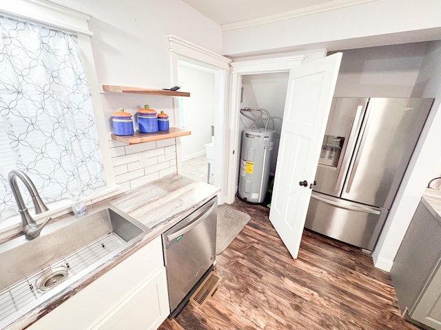 kitchen featuring sink, crown molding, appliances with stainless steel finishes, dark hardwood / wood-style flooring, and water heater