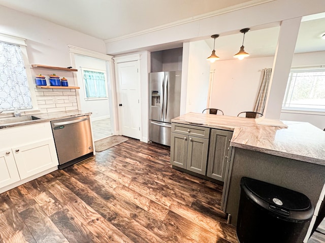 kitchen with pendant lighting, sink, stainless steel appliances, dark hardwood / wood-style floors, and tasteful backsplash