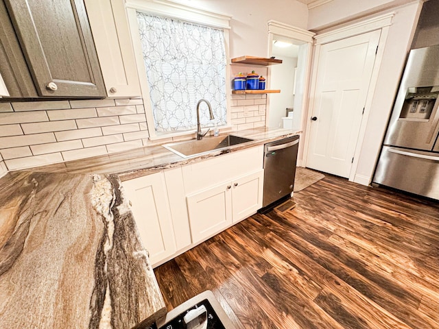 kitchen with sink, dark wood-type flooring, stainless steel appliances, white cabinets, and decorative backsplash