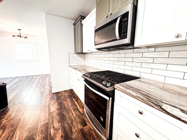 kitchen featuring appliances with stainless steel finishes, pendant lighting, tasteful backsplash, white cabinets, and dark wood-type flooring