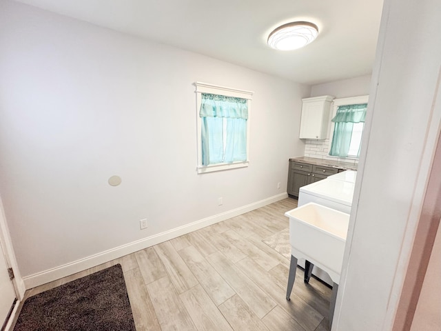 laundry area with sink, cabinets, and light wood-type flooring