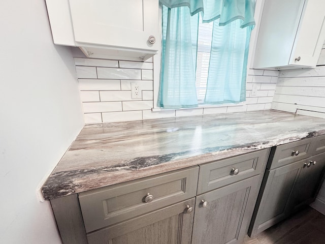 kitchen with backsplash, gray cabinets, light stone countertops, and white cabinets