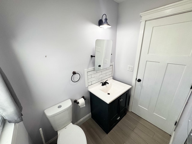 bathroom featuring vanity, hardwood / wood-style floors, tasteful backsplash, and toilet