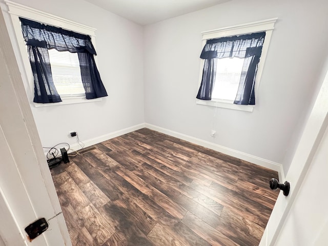 empty room with dark wood-type flooring and a wealth of natural light