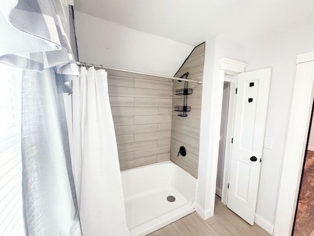 bathroom with curtained shower, vaulted ceiling, and hardwood / wood-style flooring