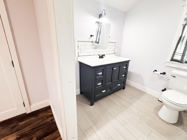 bathroom with wood-type flooring, toilet, vanity, and backsplash