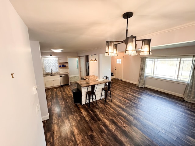 dining area featuring an inviting chandelier, sink, dark hardwood / wood-style flooring, and ornamental molding