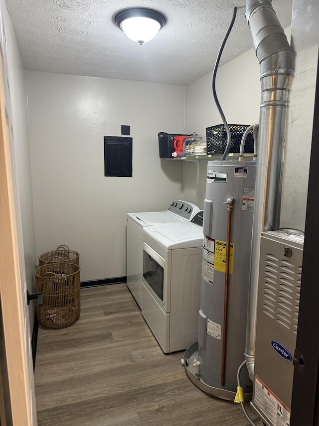 laundry room featuring hardwood / wood-style flooring, electric panel, electric water heater, washer and dryer, and a textured ceiling