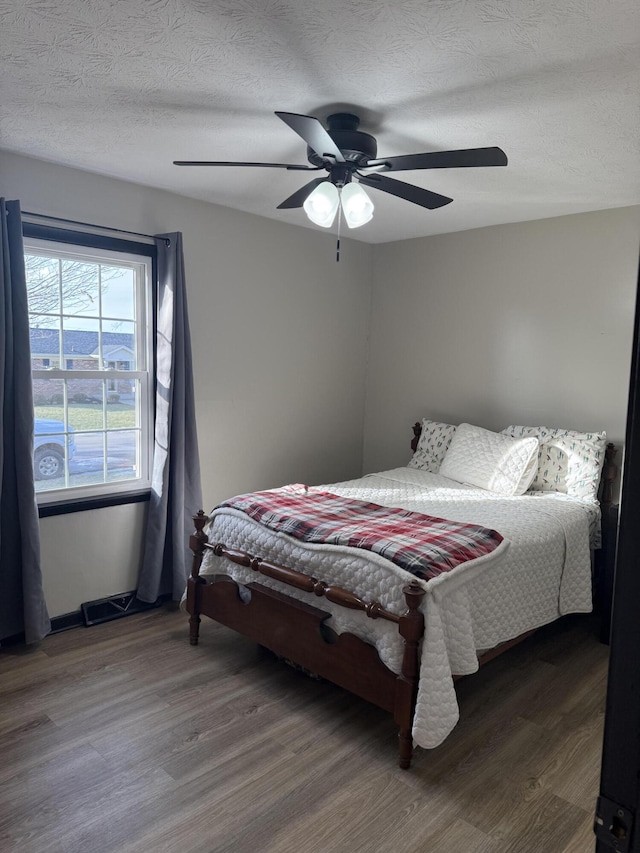 bedroom featuring ceiling fan, hardwood / wood-style floors, and a textured ceiling