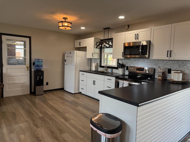 kitchen featuring dark hardwood / wood-style floors, sink, white cabinets, hanging light fixtures, and stainless steel appliances