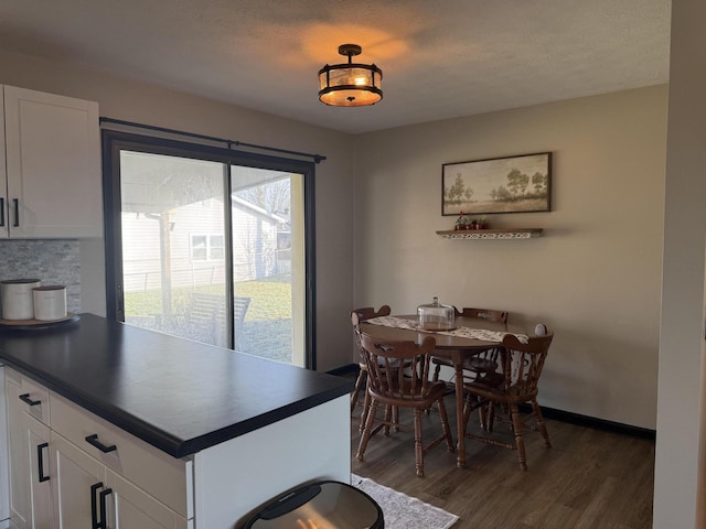 dining space featuring dark wood-type flooring and a textured ceiling