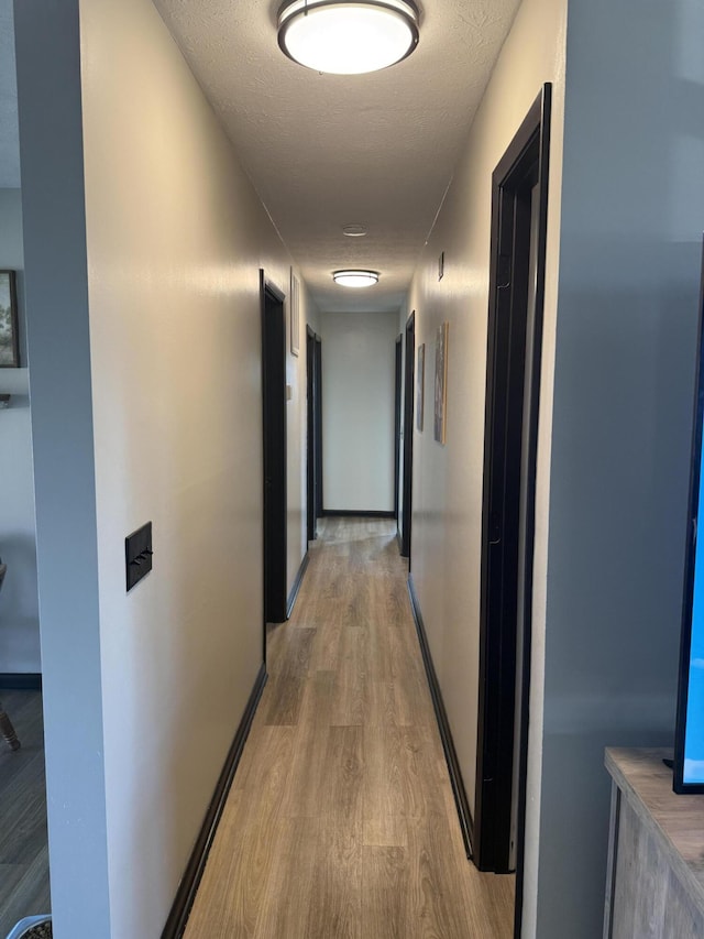 hall featuring light hardwood / wood-style floors and a textured ceiling