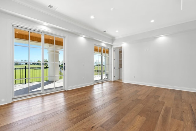 empty room with hardwood / wood-style flooring, ornamental molding, and plenty of natural light