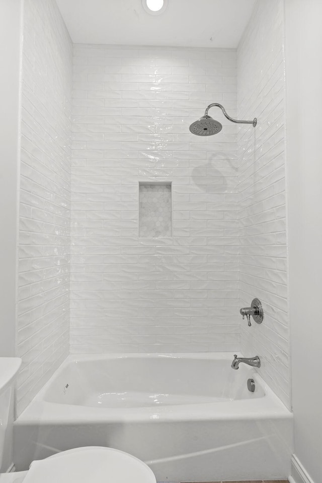 bathroom featuring toilet and tiled shower / bath